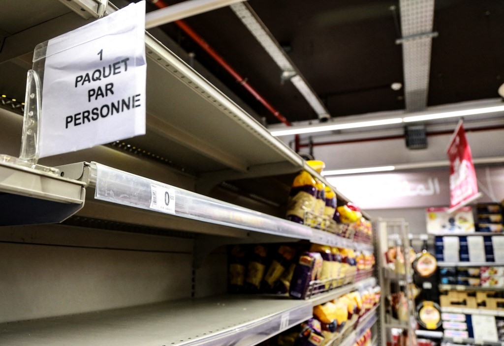 Une pancarte est placée sur des étagères presque vides de pain et d’autres produits alimentaires à base de blé indiquant en français « un sac par personne », dans un supermarché de Tunis, le 13 mars 2022 (AFP/Anis Mili)