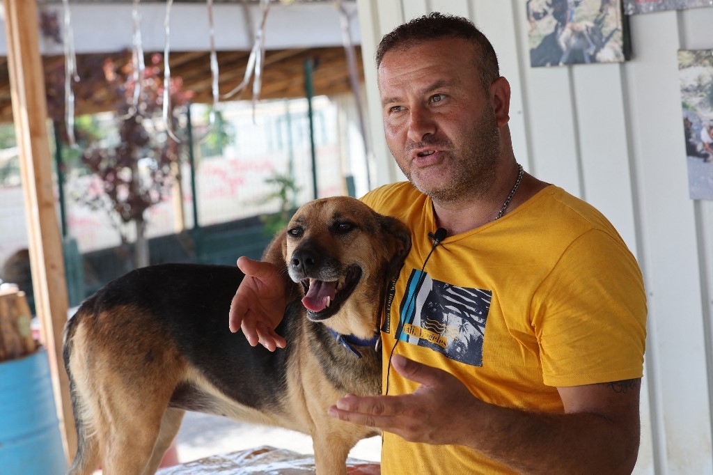 Volkan Koç, fondateur du refuge Patilikoy à Ankara, se tient à côté de Bulut (nuage en turc), l’un des chiens qu’il a sauvés, le 23 août 2022 (AFP/Adem Atlan)