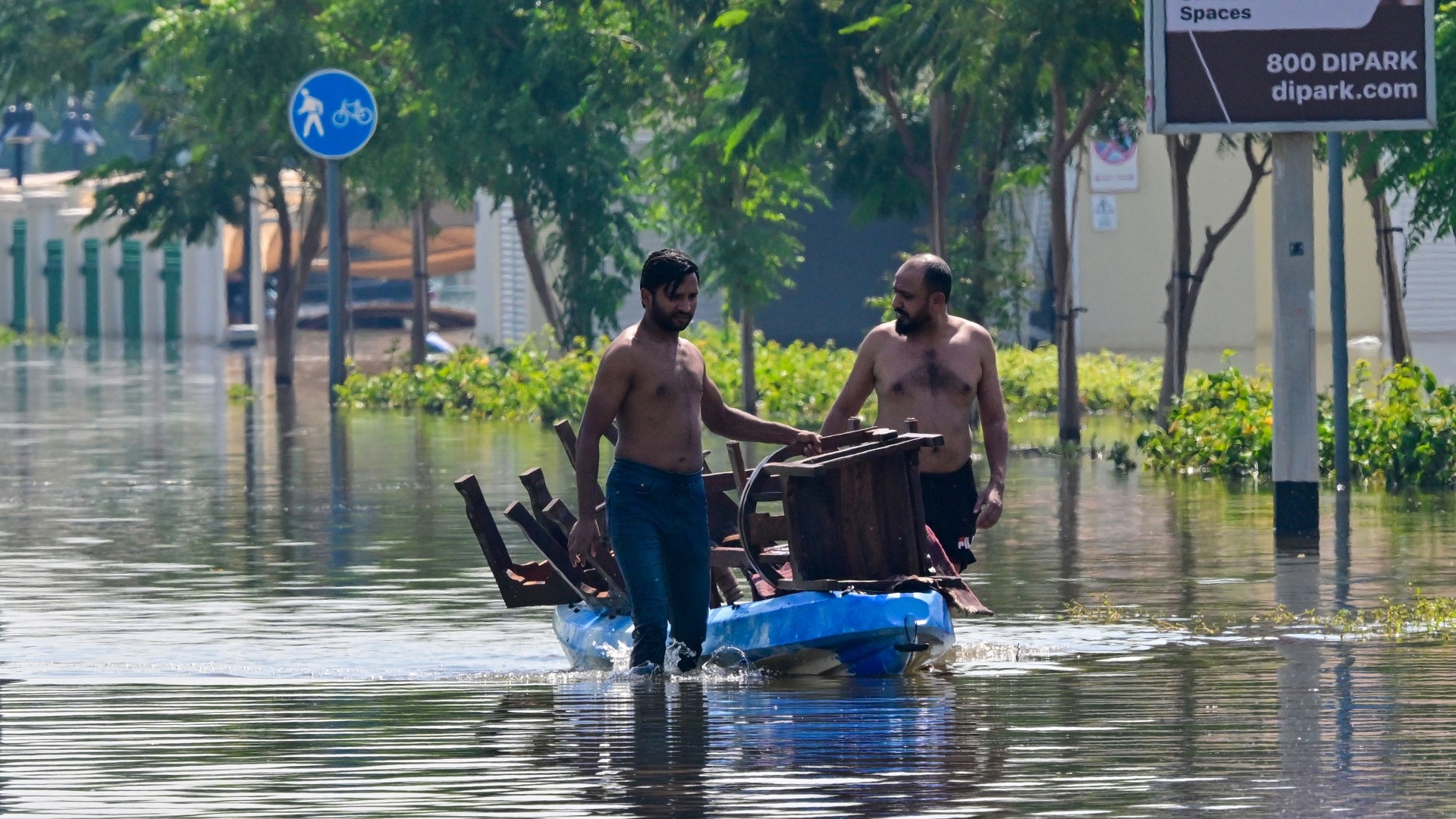 Men transport salvaged belongings in a canoe along a flooded street in Dubai on 29 April 2024 (AFP/Giuseppe Cacace)