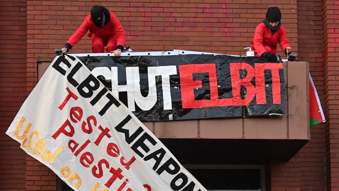 Activists from Extinction Rebellion North and Palestine Action fix a banner as they protest outside the Elbit Ferranti factory in waterhead, Oldham in north-west England on 1 February 2021.