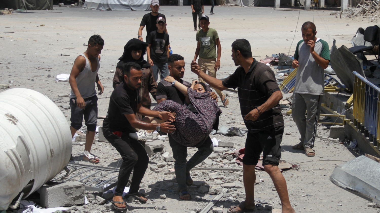 Palestinians carry a casualty outside a Unrwa headquarter following an Israeli strike on 23 June 2024 (Reuters/Mahmoud Issa)