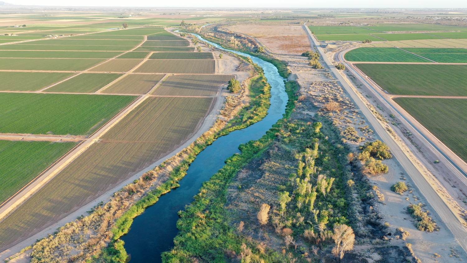 An aerial view of the long-depleted Colorado River as it flows past farmland along the border between California (R) and Arizona on 25 May 2023 near Yuma, Arizona.