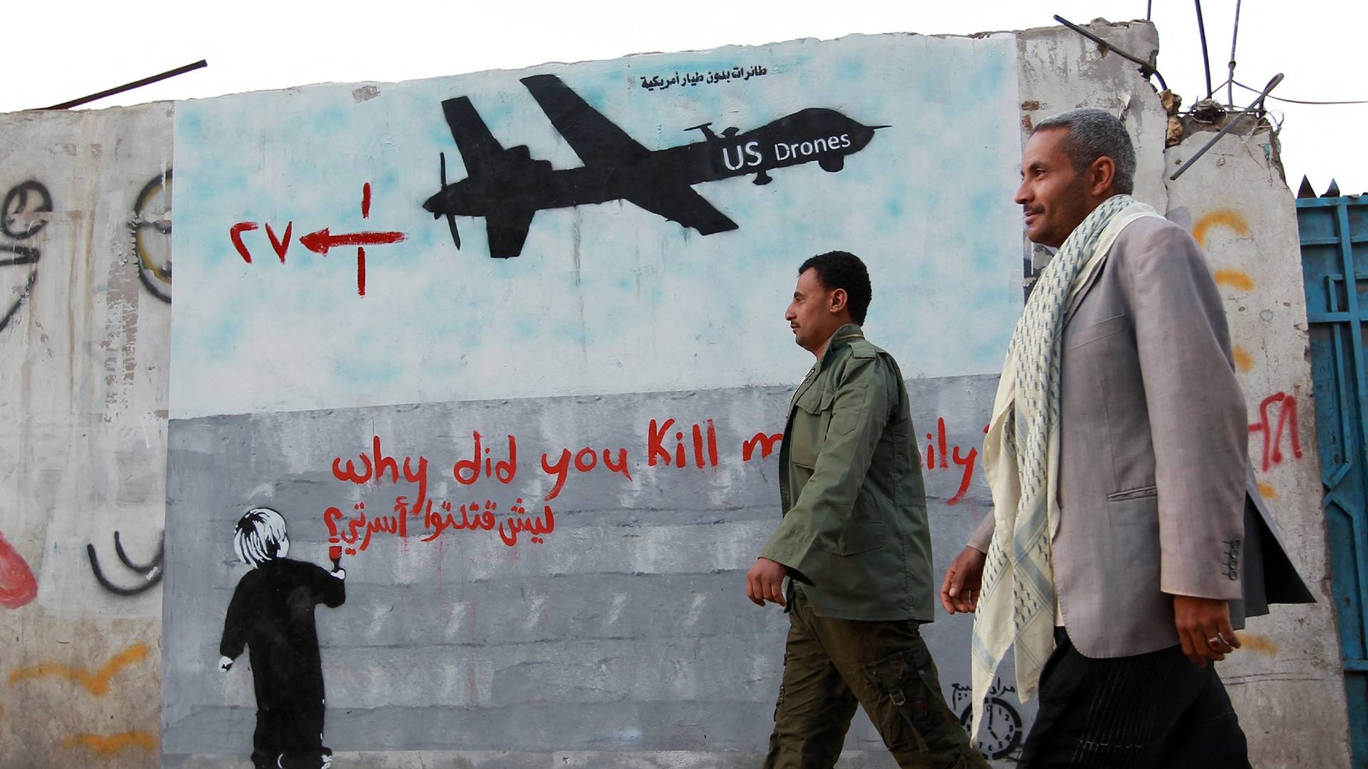 Yemeni men walk past a mural depicting a US drone and reading " Why did you kill my family" on 13 December 2013 in the capital Sanaa.