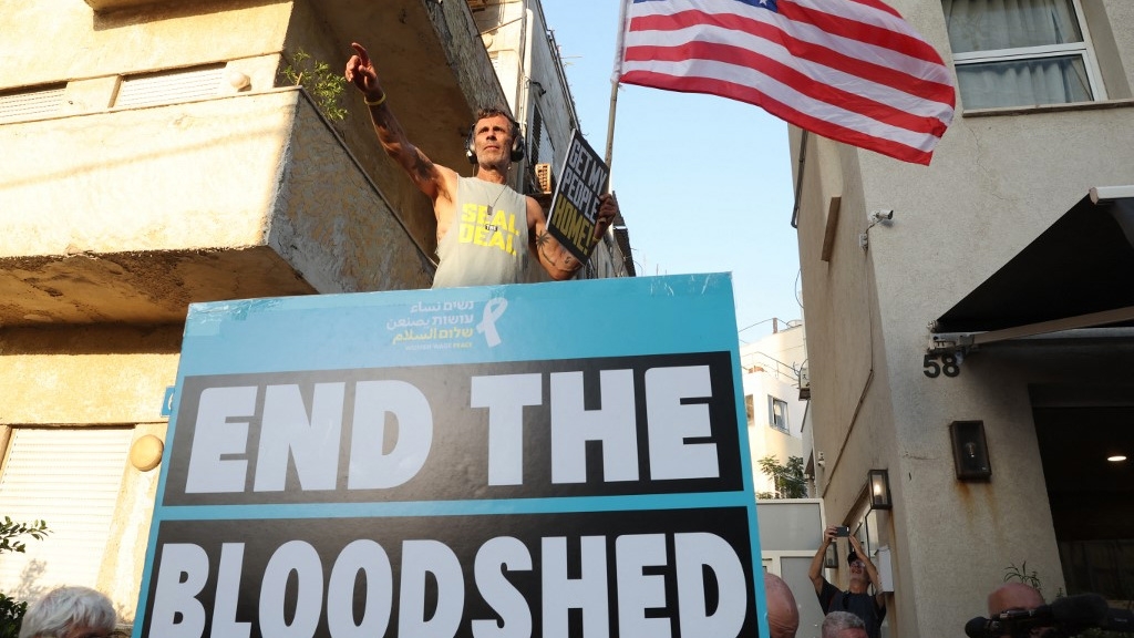 A protester waves the US flag during a gathering calling for the release of Israeli hostages in Gaza, in Tel Aviv on 19 August 2024 (Jack Guez/AFP)