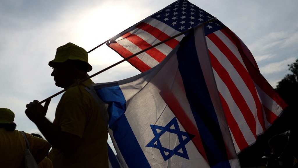 A man holds Israeli and American flags during a vigil in Washington on 23 July 2024 (Justin Sullivan/Getty Images/AFP)