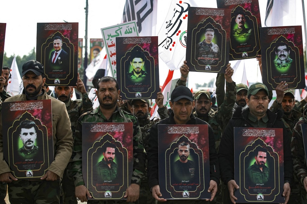 Des membres des forces paramilitaires irakiennes du Hachd al-Chaabi portent des portraits de personnes tuées lors de frappes américaines dans l’ouest de l’Irak, avant leurs funérailles à Bagdad le 4 janvier 2024 (AFP/Ahmad al-Rubaye)