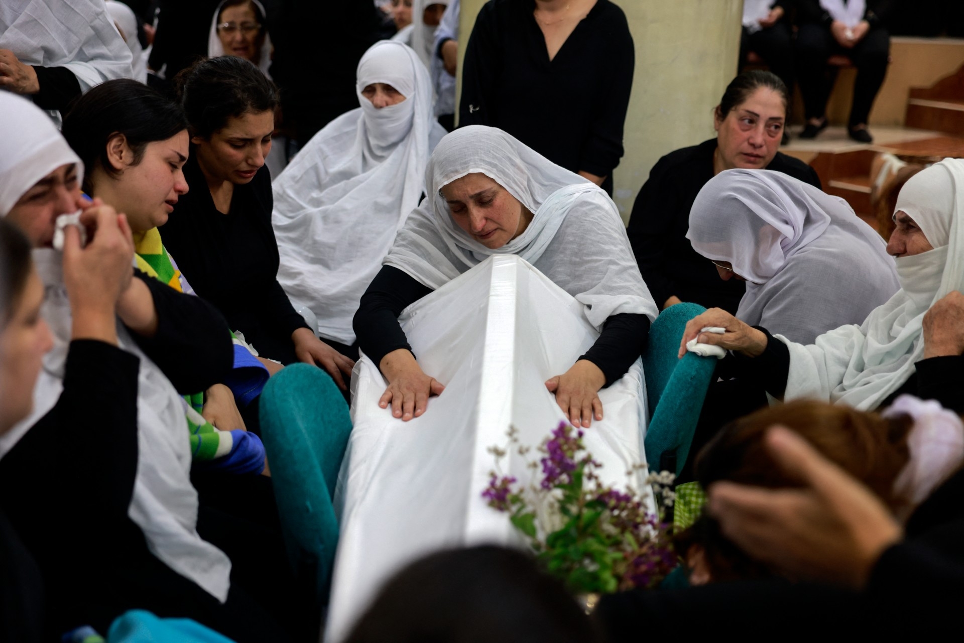 Women mourn by a coffin during a funeral in the occupied Syrian Druze town of Majdal Shams in the occupied Golan Heights on 28 July 2024 (AFP/Menahem Kahana)