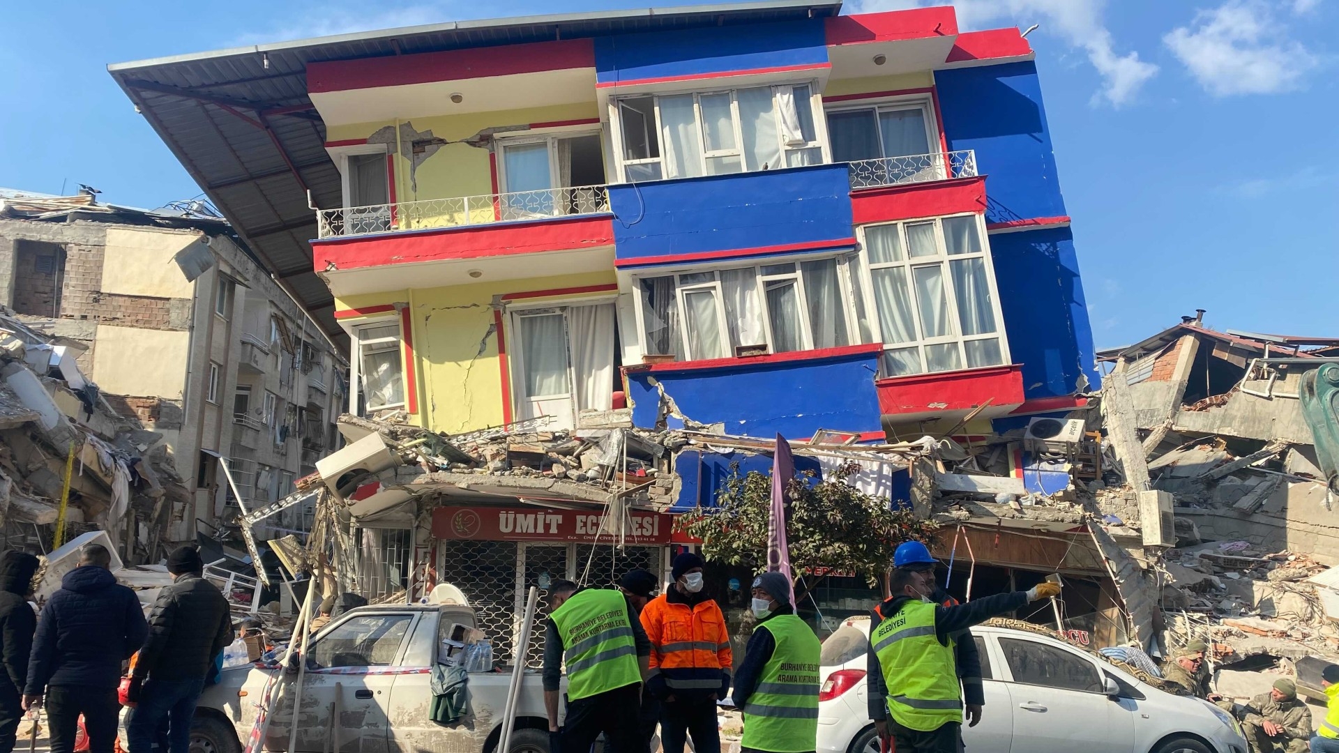 People stand near the rubble of a collapsed building in Antakya, Hatay province on 10 February 2023, four days after a 7.8 magnitude earthquake killed thousands across Turkey and Syria (MEE/Safa Ben Said)