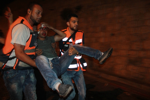 Medics carry a Palestinian man wounded in the clashes at Lion's Gate (MEE/Mahfouz Abu Turk)