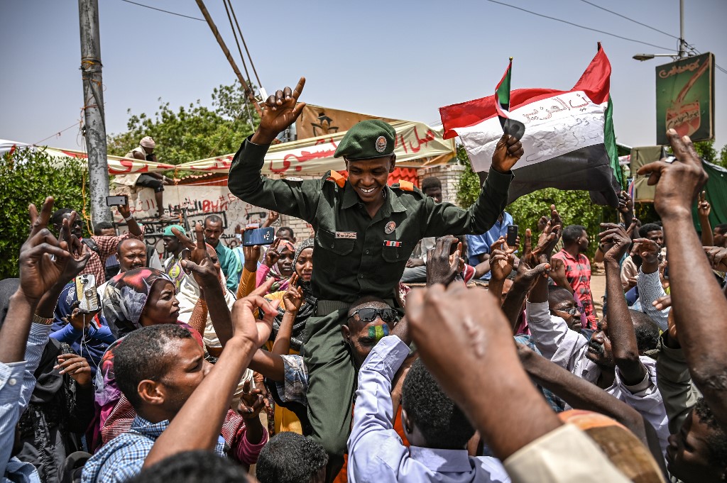 A Sudanese soldier joins protesters in Khartoum on 18 April (AFP)