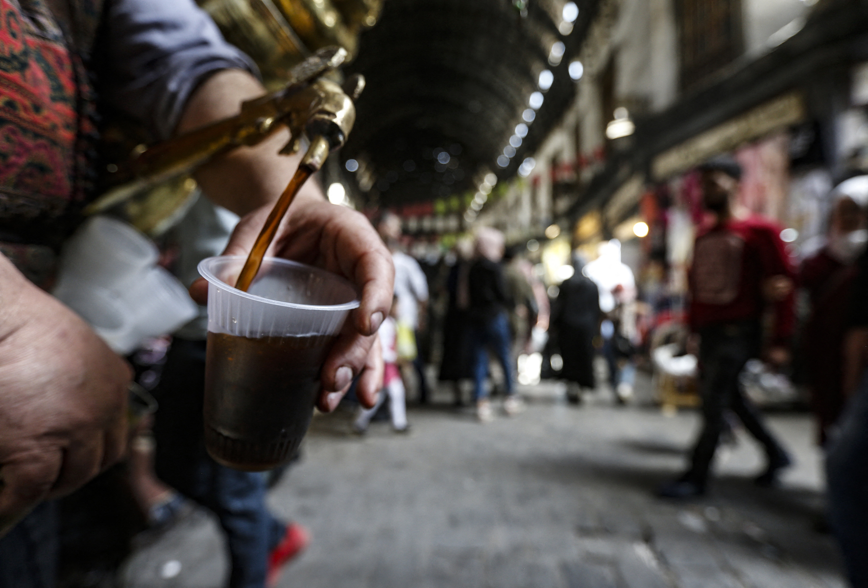 A tamarind juice seller, pours some tamarind to a customer in the Hamidiyah market in Damascus (AFP/ Louai Beshara)