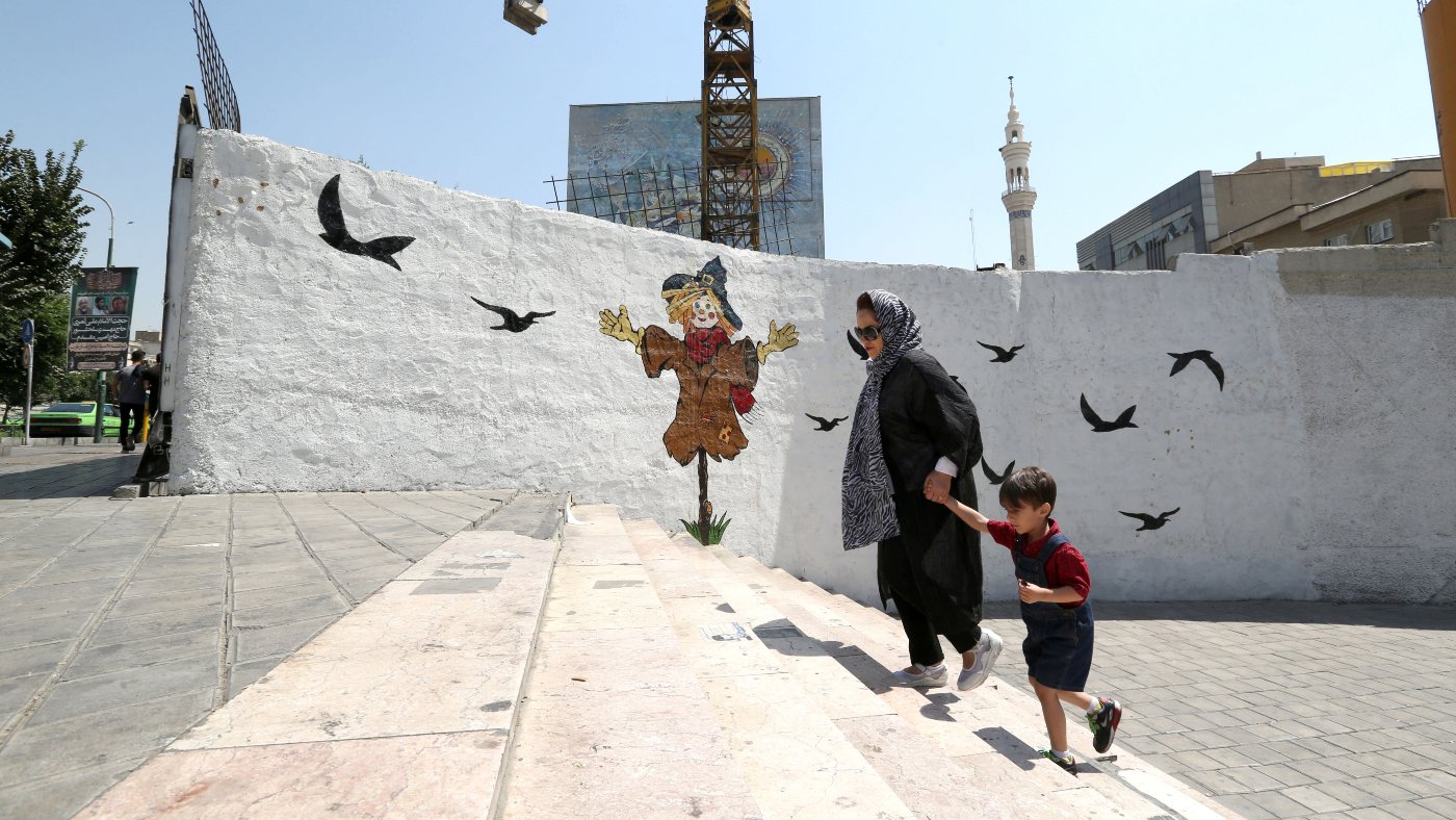 A woman holds the hand of a child as she walks up stairs at Valiasr square in the Iranian capital Tehran on 27 August 2019 (AFP)
