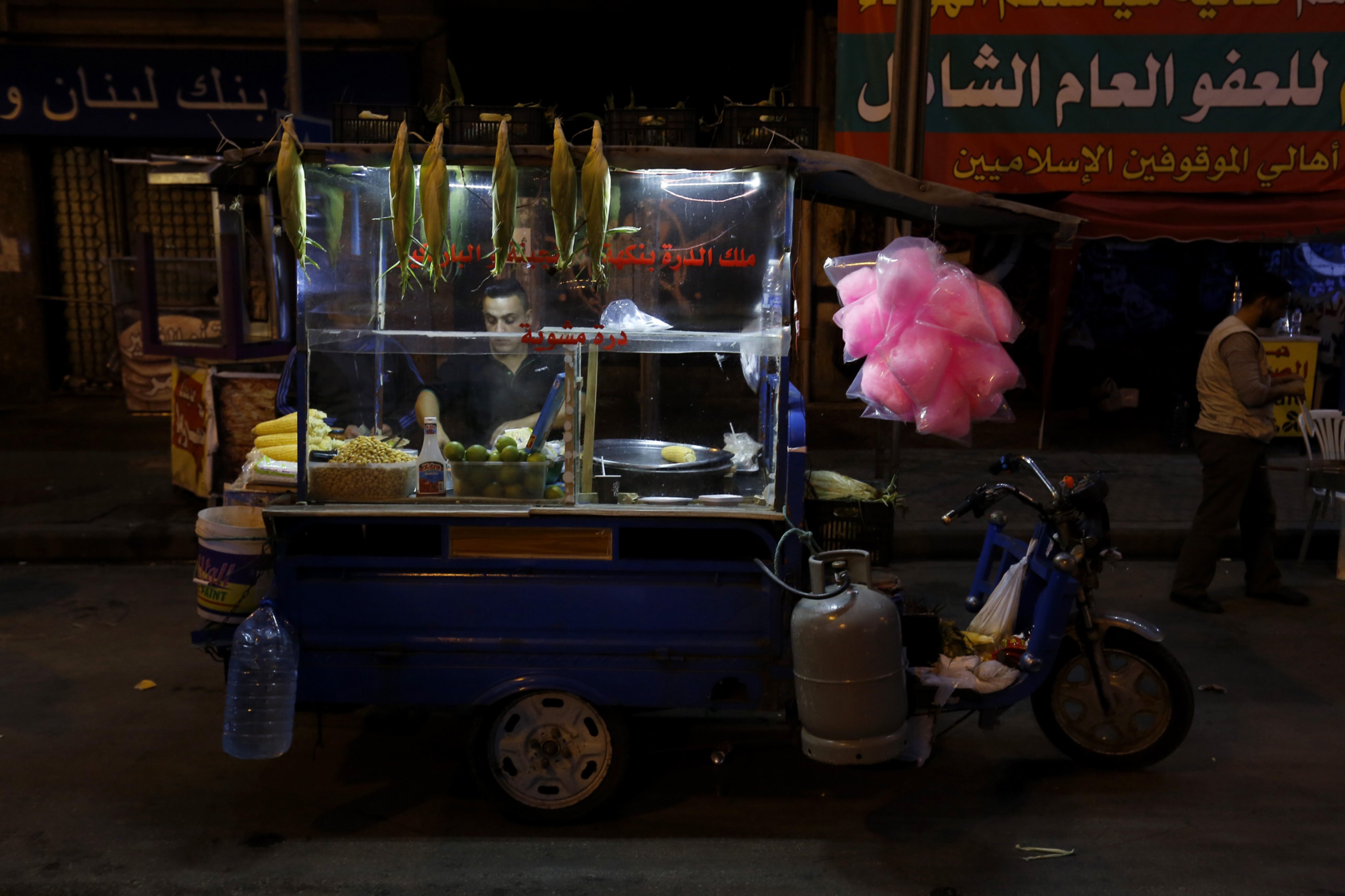 Un vendeur de rue s’occupe de son étal qui propose du maïs et des tramousses à Tripoli, au Liban (MEE/Marwan Tahtah)