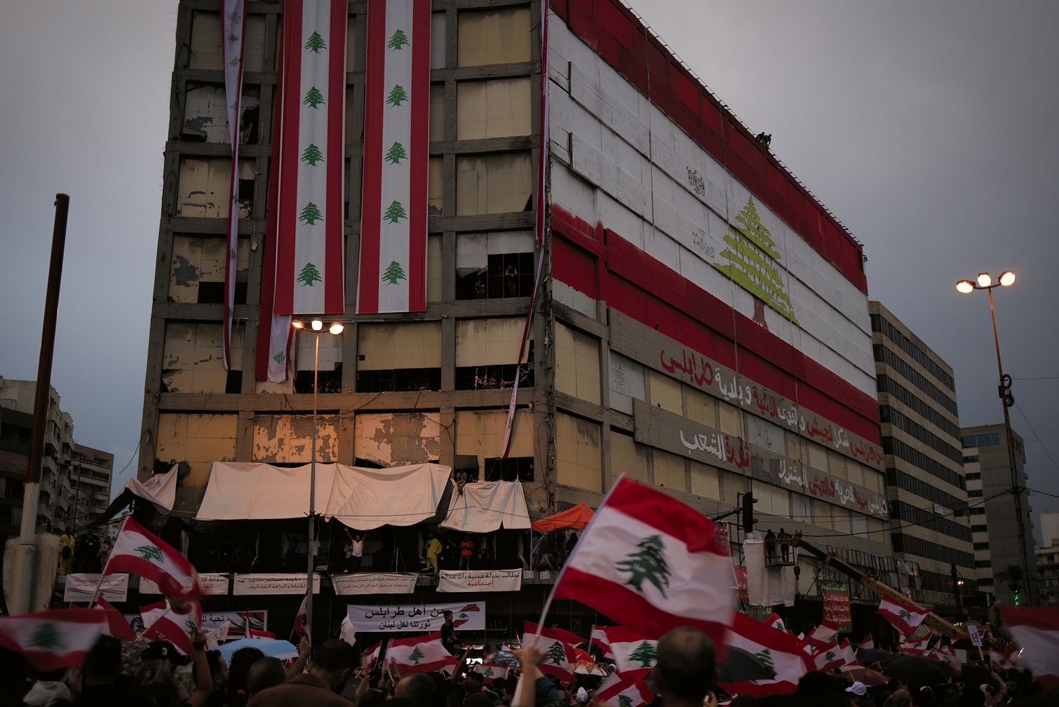 L’immeuble Ghandour, laissé à l’abandon, sert de support pour l’expression collective des protestataires : slogans, peintures et drapeaux nationaux remplacent les affiches politiques et les portraits de Saad Hariri et d’autres personnalités du Courant du futur, Tripoli, le 20 octobre (MEE/ Pierre Raimbault)