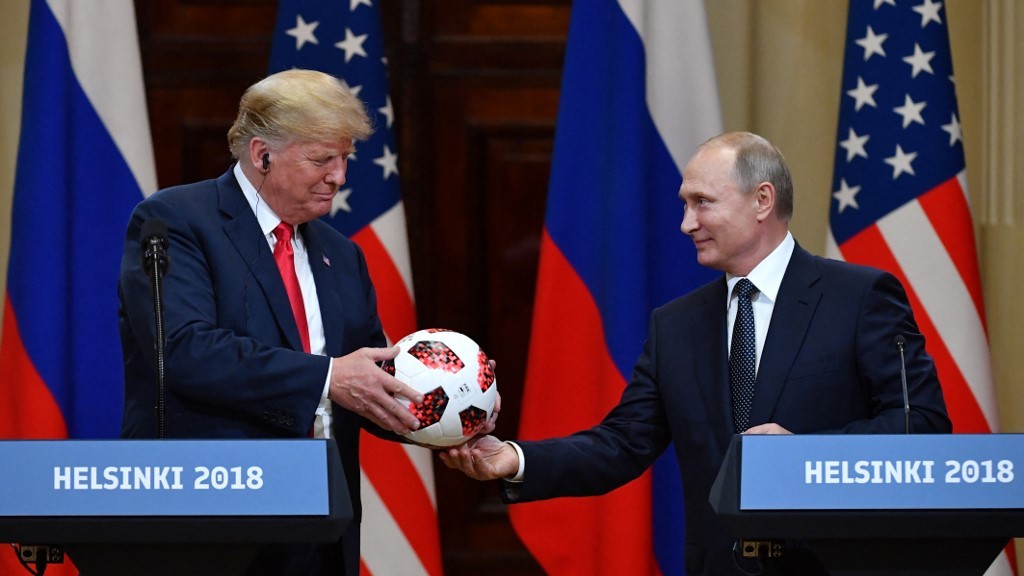 Russian President Vladimir Putin offers a ball from the 2018 World Cup to Donald Trump, then the US president, during a joint media conference in Helsinki in July 2018 (AFP)