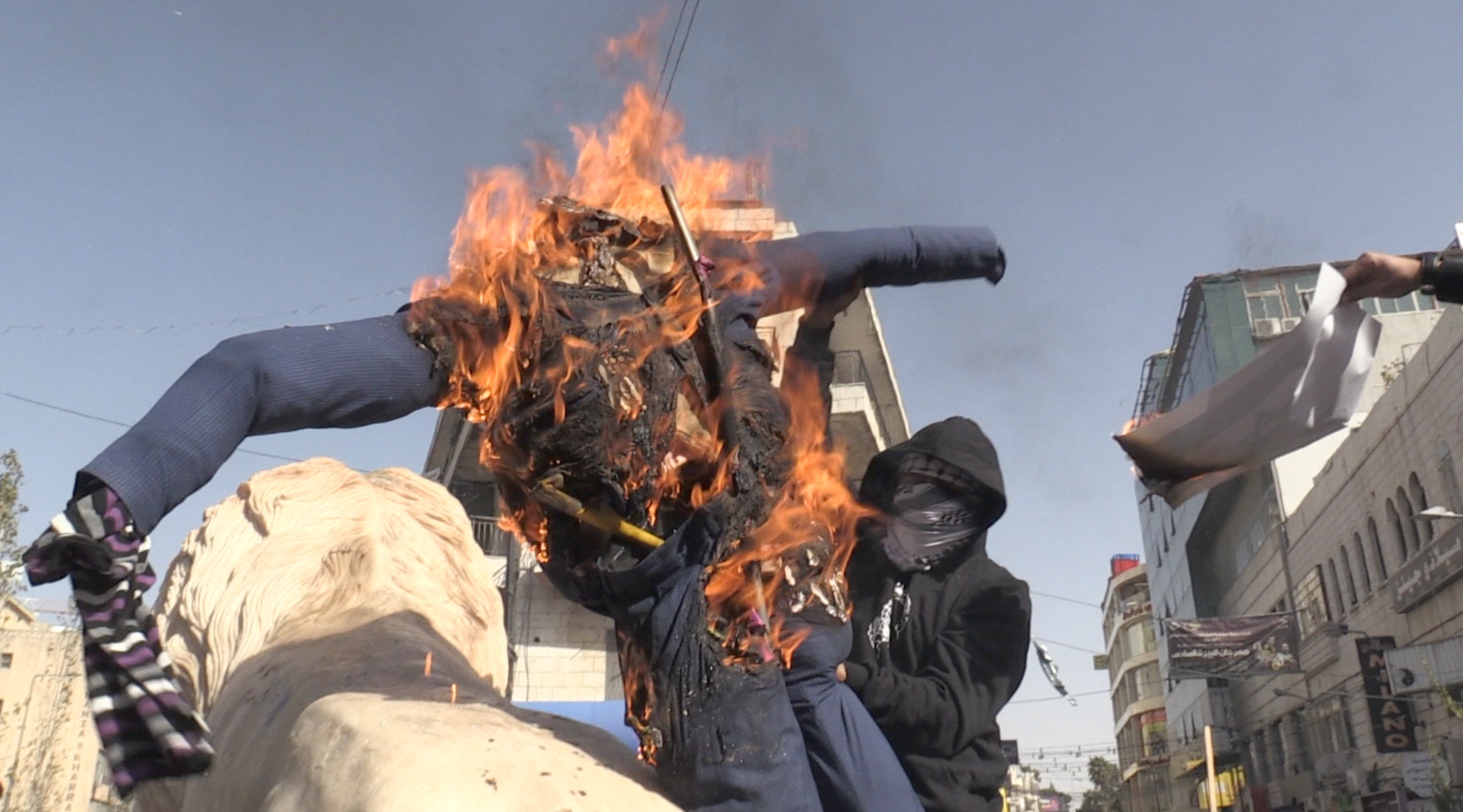 A Palestinian protester sets fire to an effigy of Donald Trump in the occupied West Bank city of Ramallah on 26 November (MEE/ Hisham Abu Shaqrah)