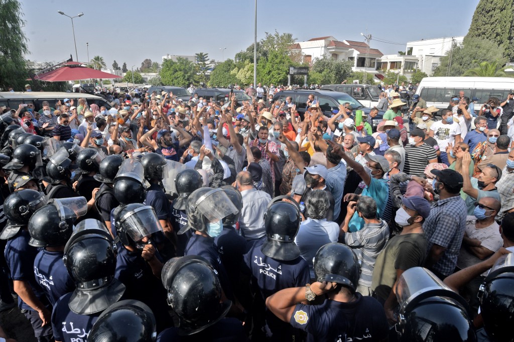 Tunisian security forces hold back protesters outside the parliament in Tunis on 26 July 2021 (AFP)