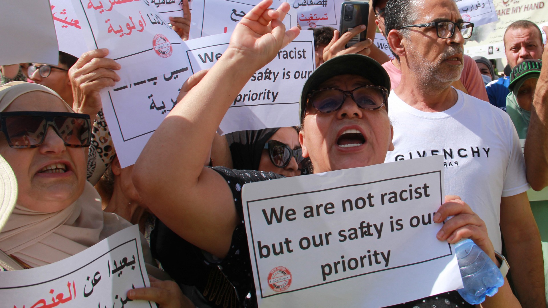 People lift placards as they shout slogans during a demonstration against the presence of illegal sub-Saharan migrants, in Sfax on June 25, 2023. 