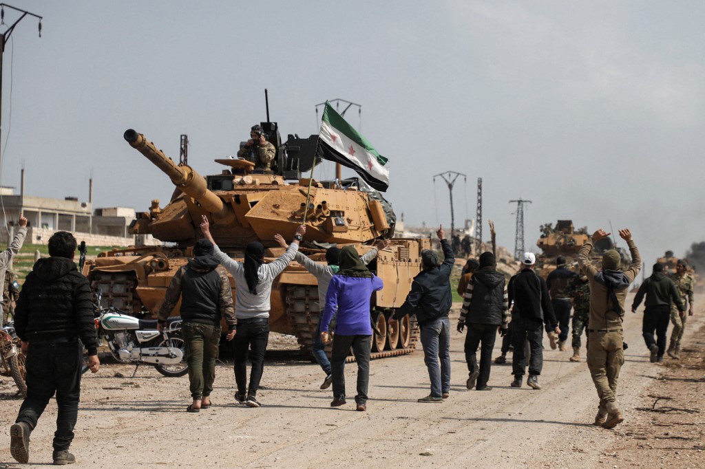 Syrians surround a Turkish military tank in northern Syria on 15 March 2020 (AFP)