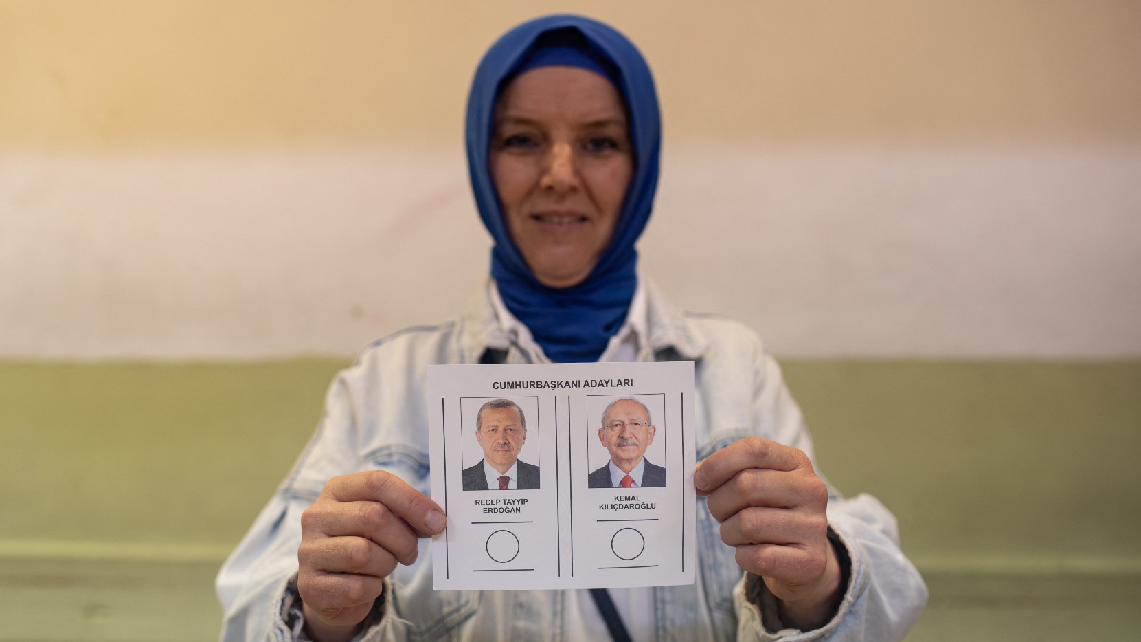 A woman holds ballot papers showing Turkish presidential candidates Recep Tayyip Erdogan (R) and Kemal Kilicdaroglu at a polling station in Kocaeli on 28 May (AFP)