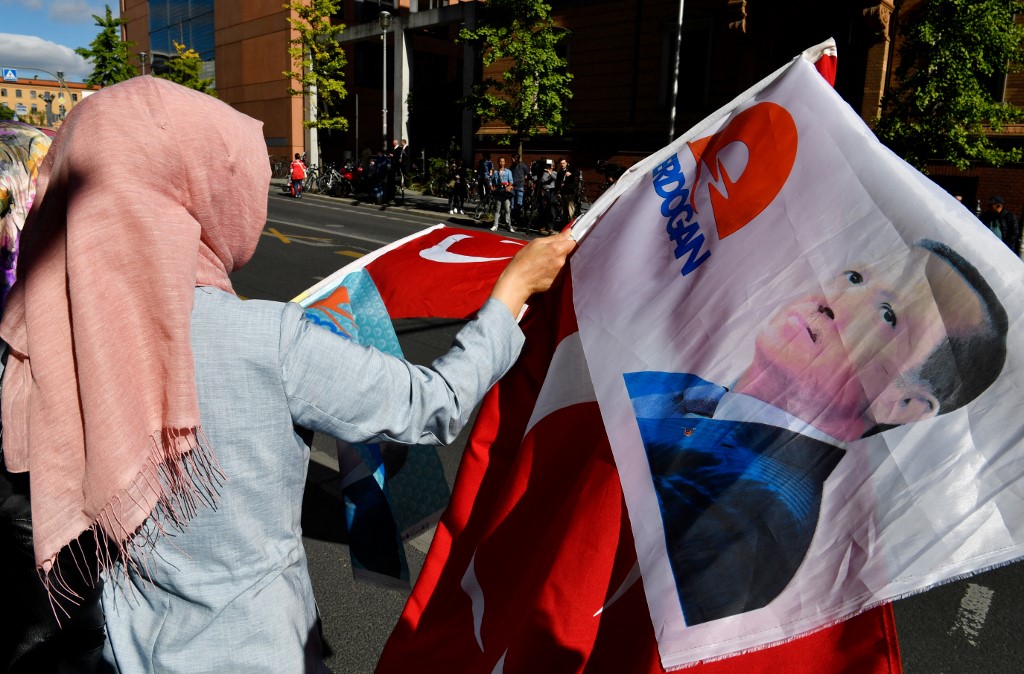 A woman wearing a headscarf waves a flag bearing a portrait of Turkish President Recep Tayyip Erdogan in Berlin in September 2018 (AFP)