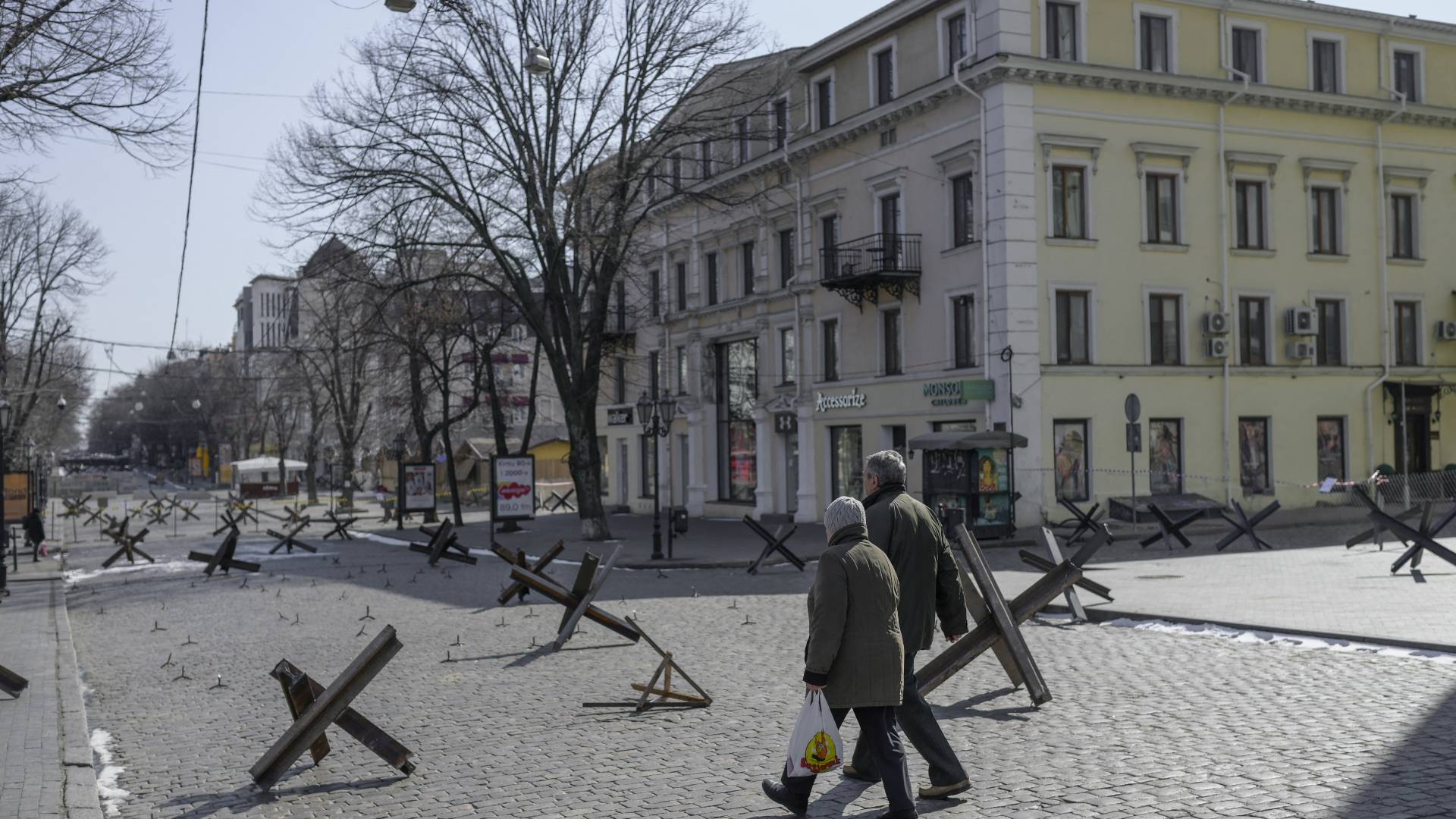 Residents cross an empty street next to anti-tank obstacles in Odessa on March 13, 2022.
