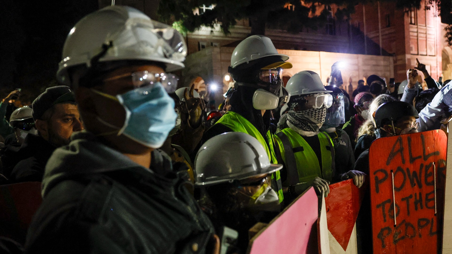 Pro-Palestine protesters can be seen donning hard hats, goggles and respirator masks at the encampment at UCLA after riot police stormed the area on 2 May, 2024 (AFP)