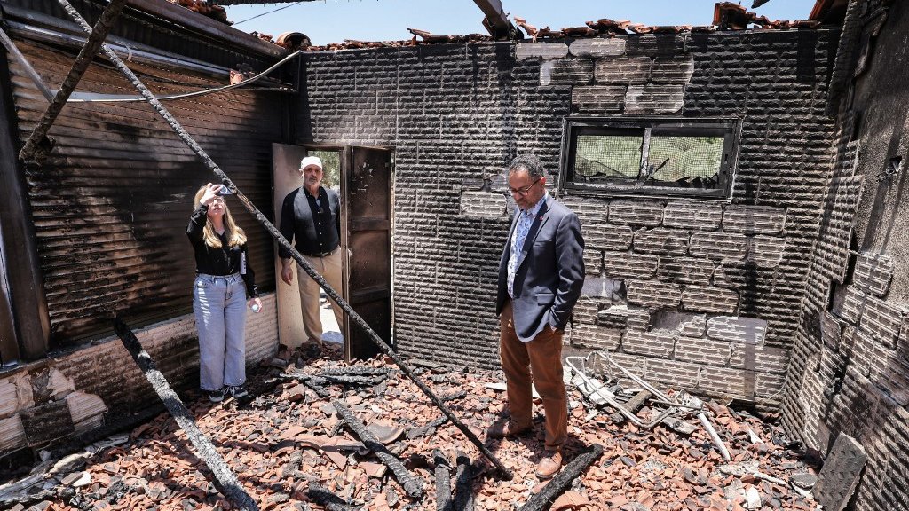 People stand inside a destroyed building in the village of Turmusaya on Friday (AFP)