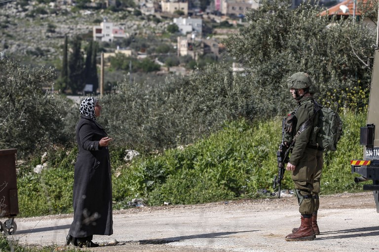 A Palestinian woman speaks with an Israeli soldier at a West Bank checkpoint on 17 March (AFP)