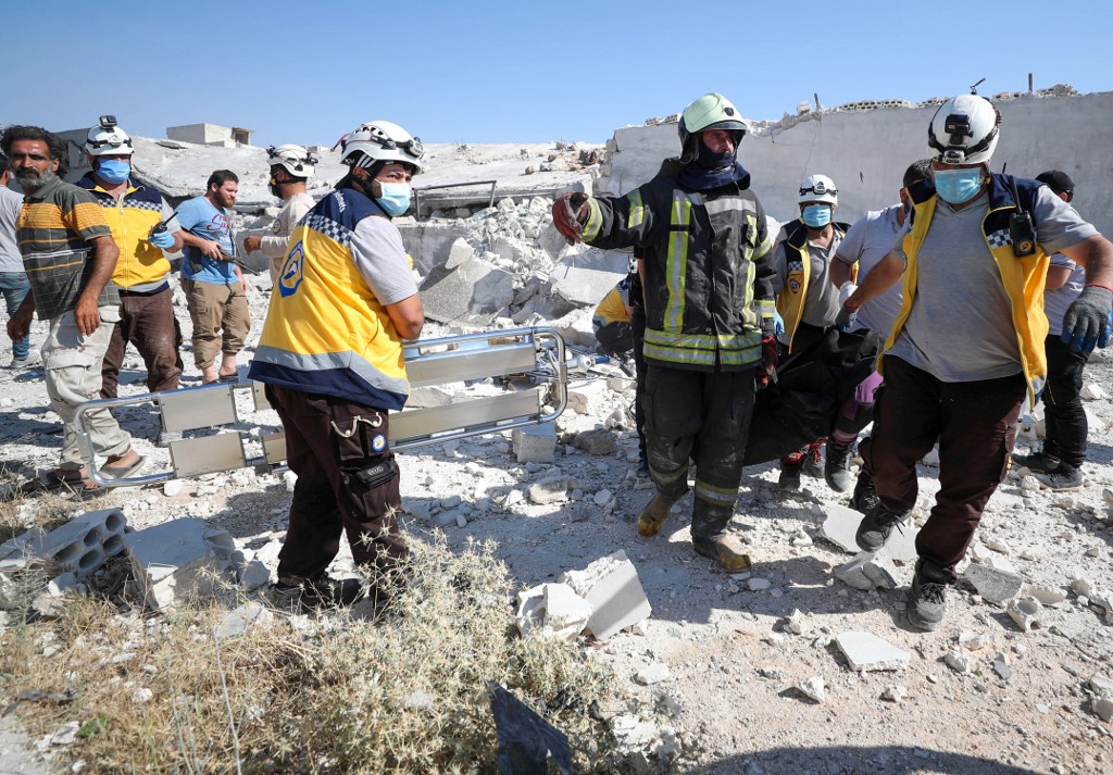 Syrian Civil Defence rescue workers, also known as White Helmets, carry a body away from the debris of a building following a reported explosion in Syria's northwestern city of Idlib on July 10, 2020.