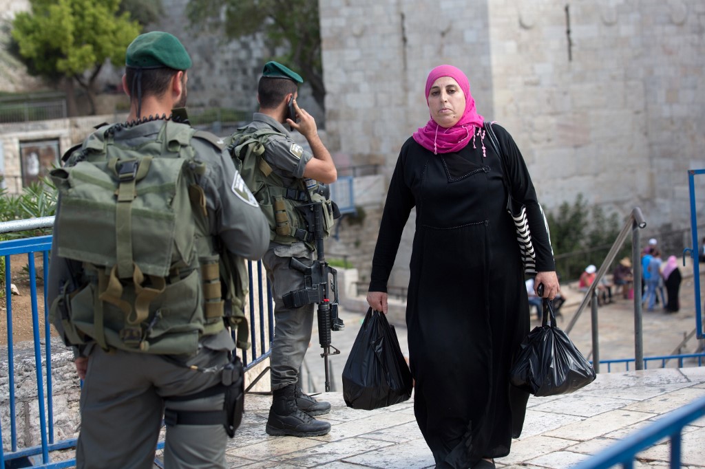 Une Palestinienne passe devant des agents de la police aux frontières israélienne à une entrée de la vieille ville, à Jérusalem-Est (AFP)