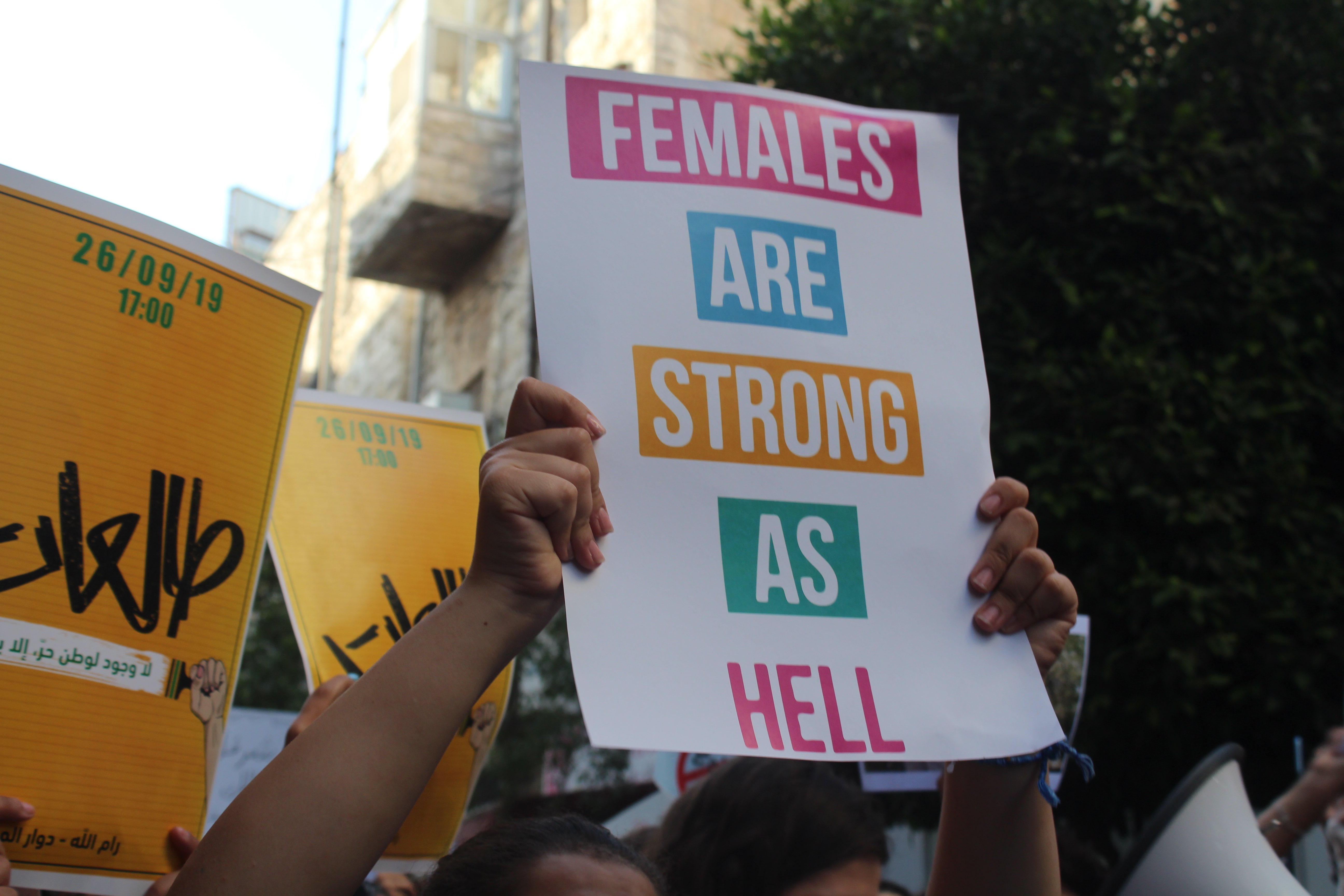 A protester holds up a sign that reads 'females are strong as hell' (MEE/Shatha Hammad)