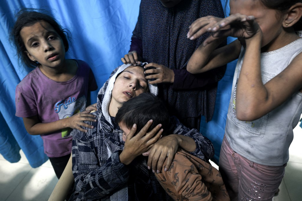 A wounded Palestinian woman is surrounded by her children at Nasser Hospital in the Gaza Strip following Israeli air strikes, 13 November 2023 (Mahmud Hams/AFP)