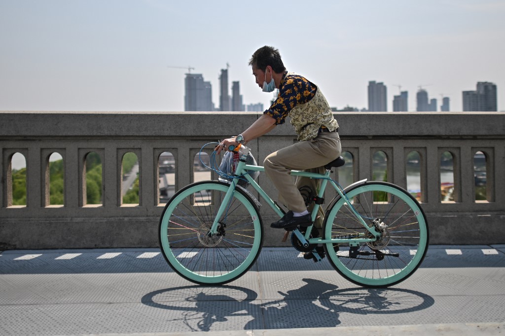 A man wearing a face mask rides a bicycle on Wuhan Bridge over the Yangtze river in Wuhan, China's central Hubei province on April 16, 2020.  (AFP)