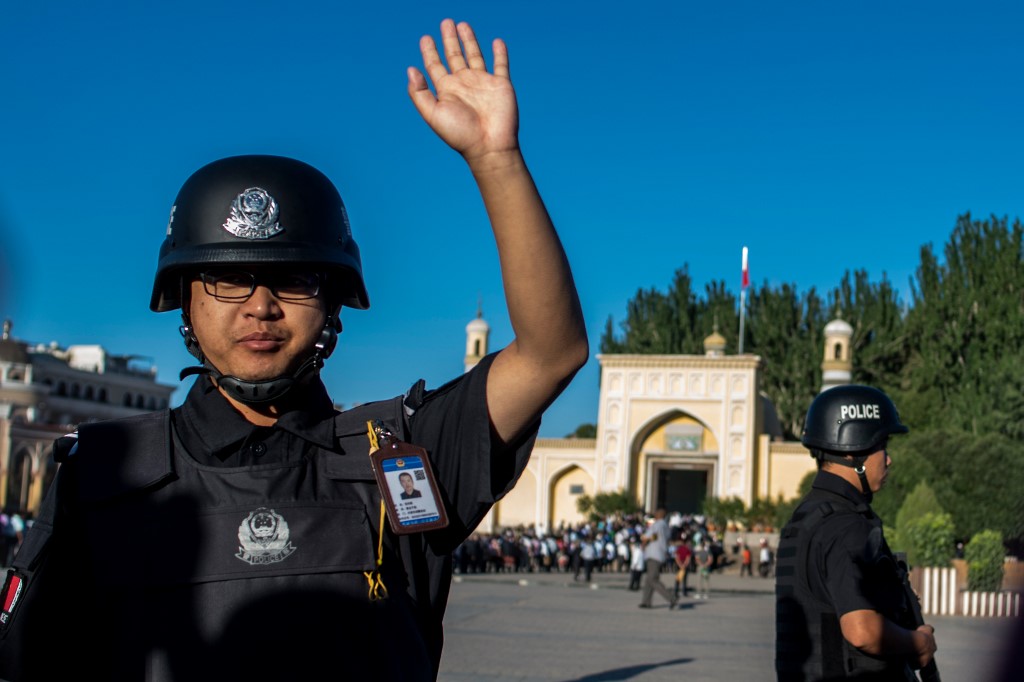 A police officer gestures as Muslims arrive at a mosque in the Xinjiang region in 2017 (AFP)