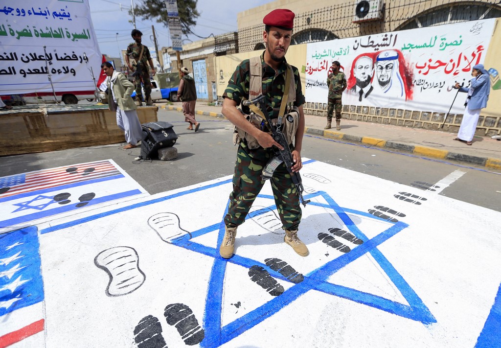 A fighter loyal to Yemen's Huthi rebels treads on US and Israeli flags painted on the ground during a rally in the capital Sanaa, on August 22, 2020, to protest the US-brokered deal to normalise Emirati-Israeli relations.